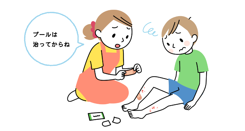 小学生の男の子のすねに「とびひ」。30代のお母さんが絆創膏を貼りながら、「プールは治ってからね」と話しかけている。