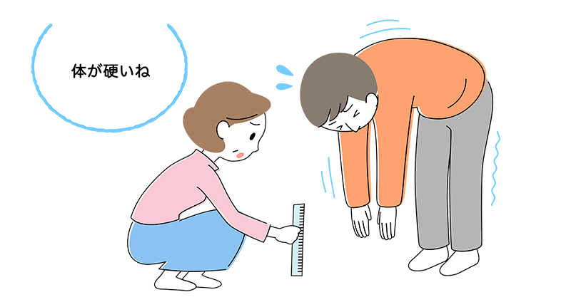 50代夫が膝を曲げずに手を伸ばして前屈し、柔軟性を見ている。隣で妻が床からの距離を定規ではかりながら「体が硬いね」と言っている。