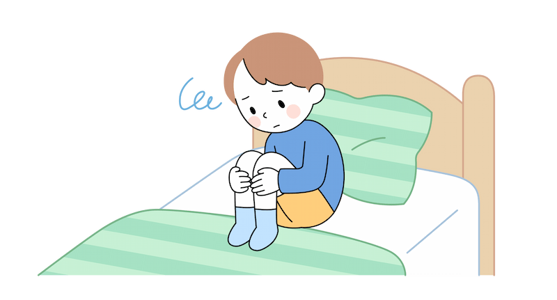 ベッドで膝をかかえてうずくまる5歳ぐらいの男の子