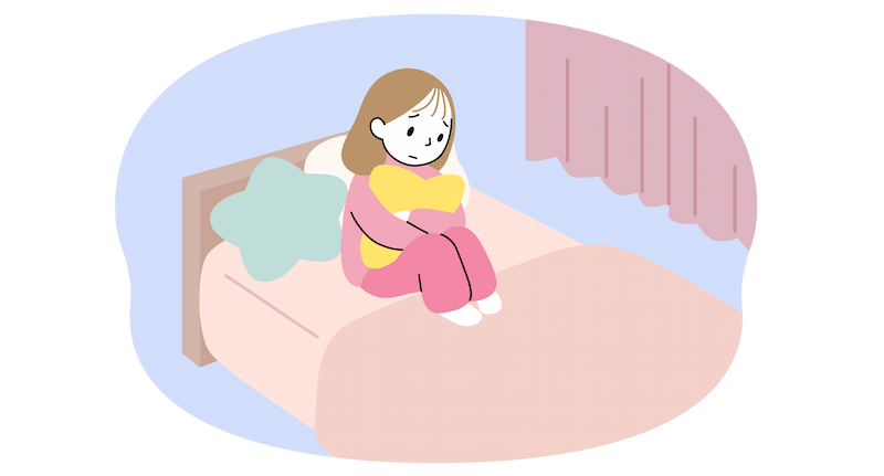 薄暗くした子ども部屋のベッドの上にクッションを並べたところにもたれかかり、安静にしている中学生女子