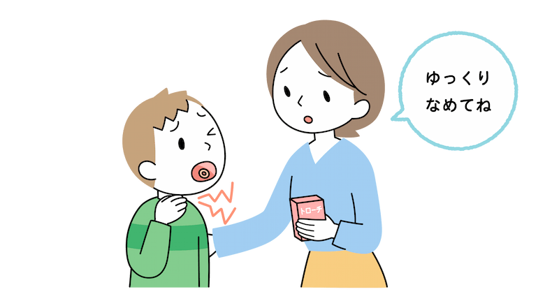 のどを痛そうにしている小学校高学年の男の子がトローチをなめている。お母さんが「ゆっくりなめてね」と助言