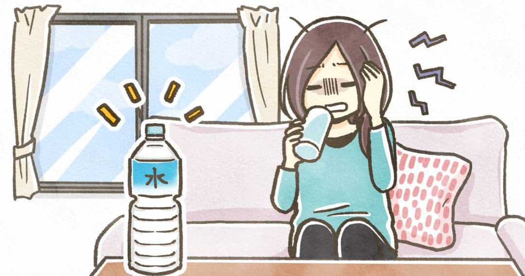 二日酔いで辛い状態で水分補給をする女性