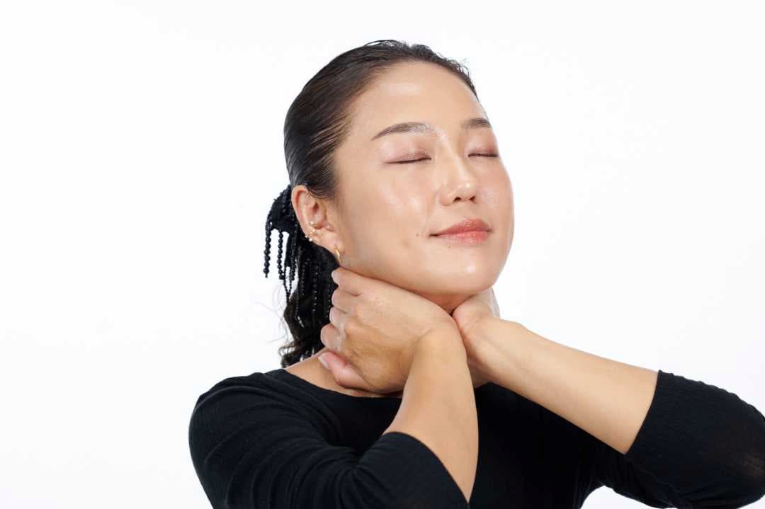 両手で首を優しく包み込むようにして保湿ケアをしている写真