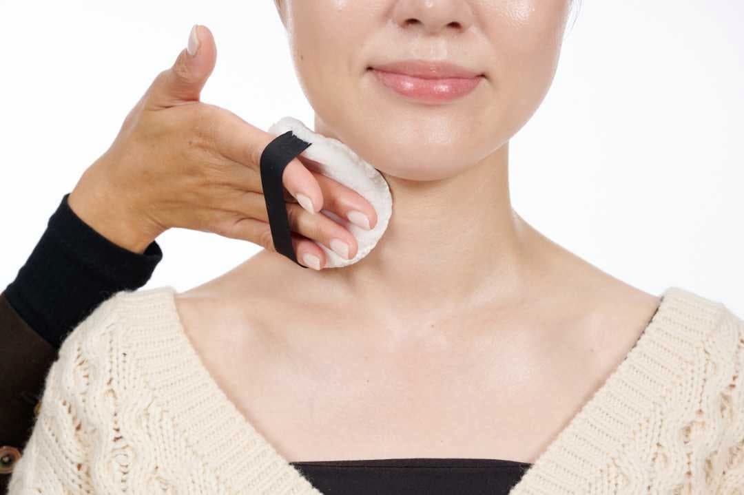 パフを使って首にパウダーをはたいている写真